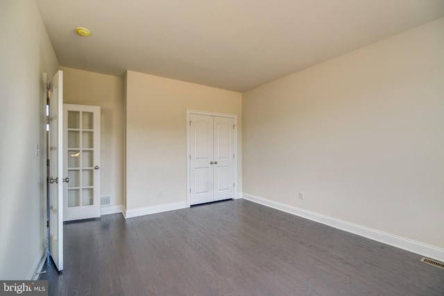 empty room featuring french doors and dark hardwood / wood-style flooring