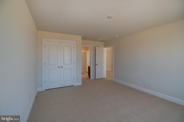 unfurnished bedroom with light carpet and a closet