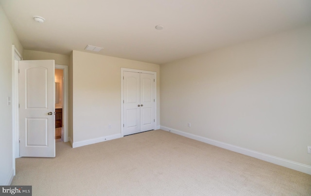 unfurnished bedroom with a closet and light colored carpet