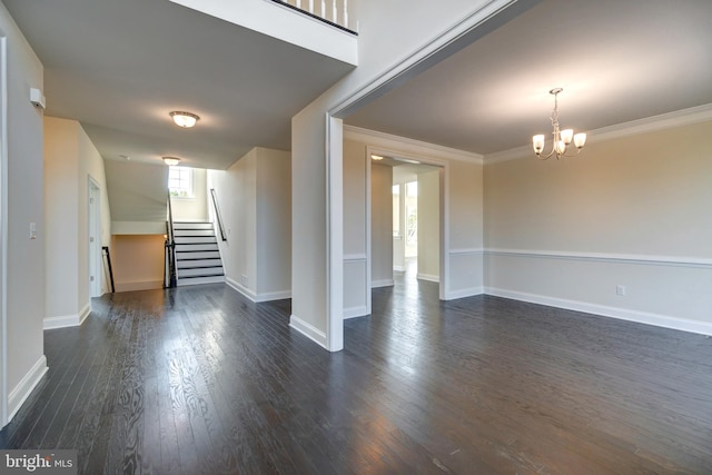 spare room featuring a notable chandelier, dark wood-type flooring, and a healthy amount of sunlight