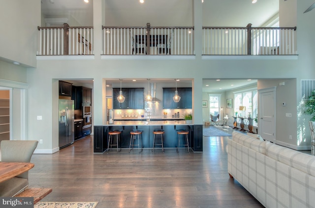 living room featuring dark wood-type flooring, sink, and a towering ceiling