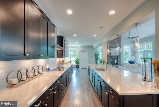 kitchen featuring pendant lighting, sink, light hardwood / wood-style flooring, a fireplace, and tasteful backsplash