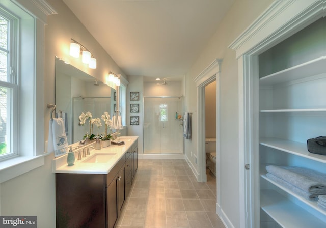 bathroom featuring walk in shower, toilet, tile floors, and dual bowl vanity