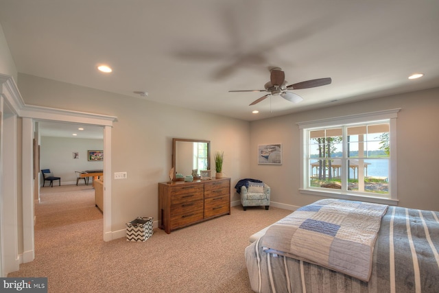 bedroom featuring ceiling fan, a water view, and light carpet