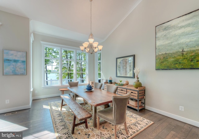 dining room with dark wood-type flooring, ornamental molding, a notable chandelier, and high vaulted ceiling