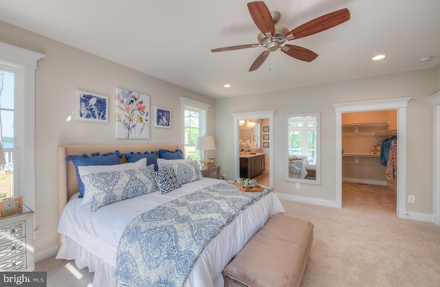 carpeted bedroom featuring ceiling fan, a walk in closet, ensuite bathroom, and a closet