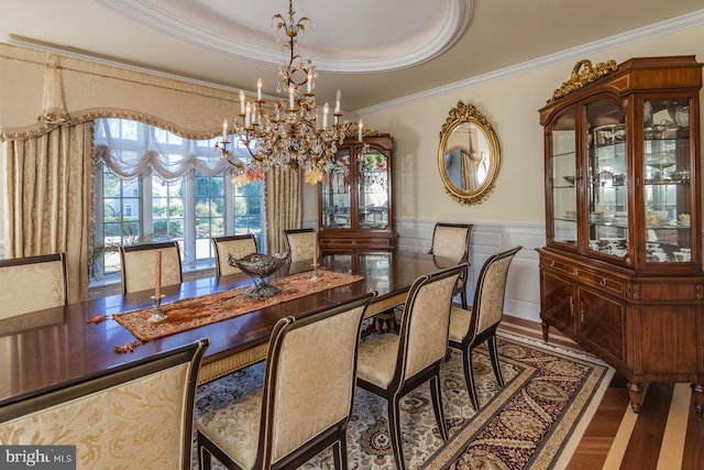 dining room with an inviting chandelier, a raised ceiling, dark hardwood / wood-style flooring, and ornamental molding