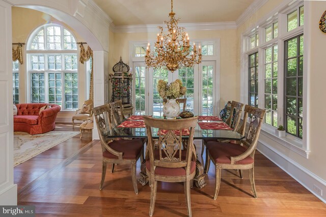 dining area with light hardwood / wood-style floors, ornamental molding, a chandelier, and a healthy amount of sunlight