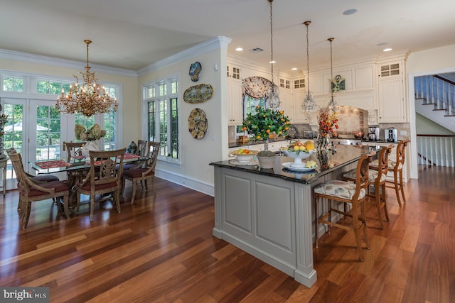 kitchen featuring dark stone counters, dark wood-type flooring, white cabinetry, a notable chandelier, and pendant lighting