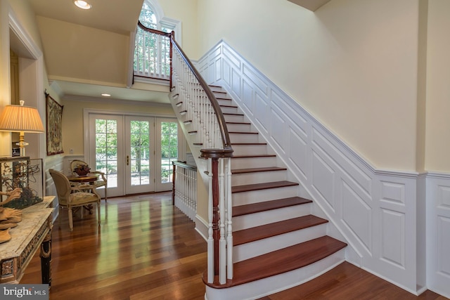 stairway with dark hardwood / wood-style flooring, french doors, and a towering ceiling