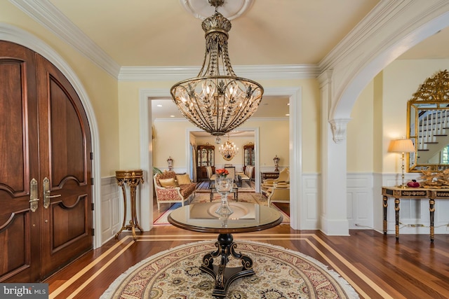 foyer featuring an inviting chandelier, crown molding, and dark hardwood / wood-style floors