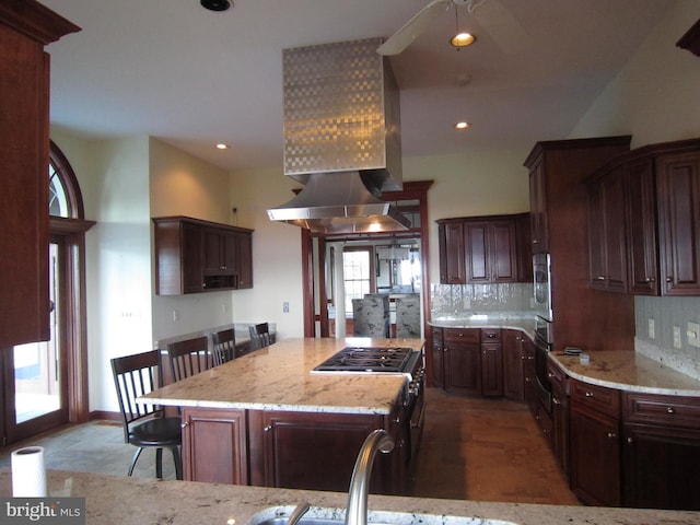 kitchen with plenty of natural light, a breakfast bar area, tasteful backsplash, and light stone countertops