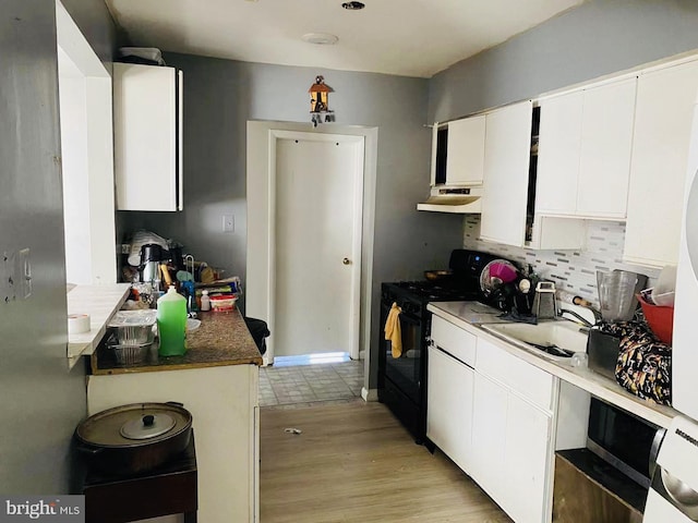 kitchen featuring white cabinets, black gas stove, light wood-type flooring, and backsplash