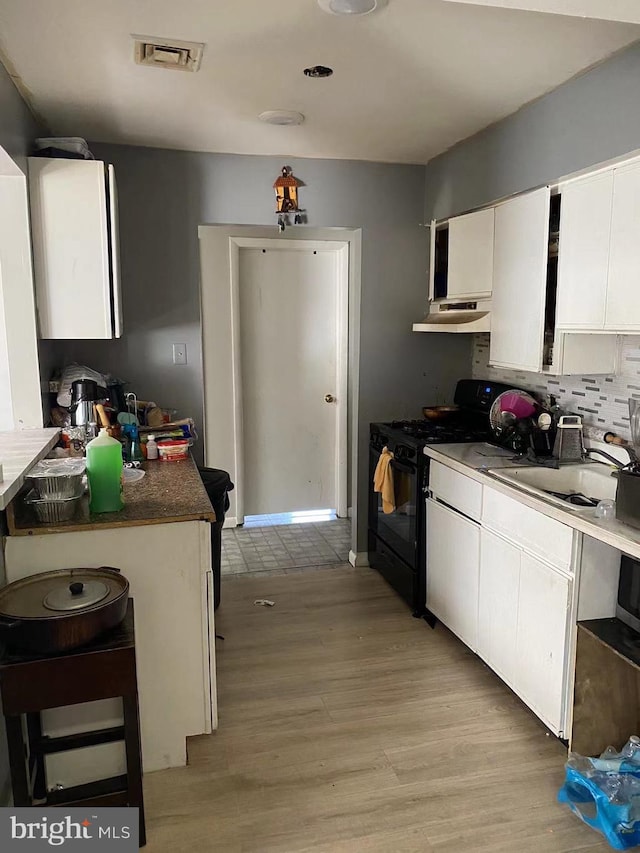 kitchen featuring a breakfast bar, backsplash, light hardwood / wood-style floors, white cabinetry, and gas stove