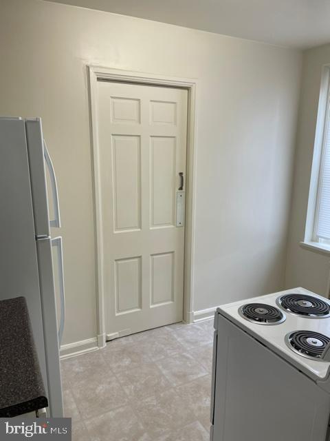 kitchen featuring white refrigerator, range, and light tile floors