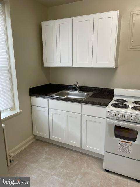 kitchen with white cabinets, sink, light tile floors, and white gas range oven