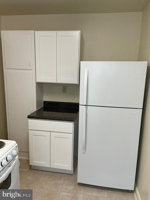 kitchen featuring white cabinets, white appliances, and light tile floors