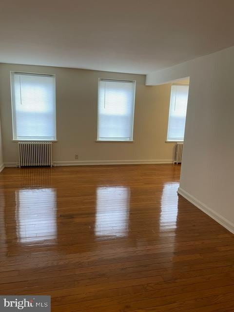 unfurnished room featuring radiator heating unit and light hardwood / wood-style floors