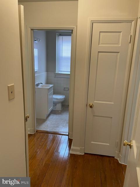 hallway featuring tile walls, sink, and dark hardwood / wood-style floors