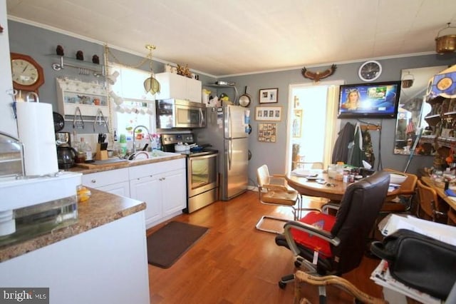 kitchen featuring light hardwood / wood-style floors, stainless steel appliances, white cabinets, crown molding, and pendant lighting