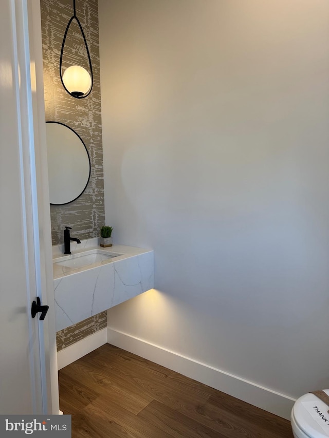 bathroom featuring toilet, a sink, baseboards, and wood finished floors