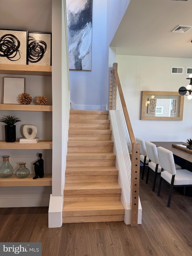 staircase featuring baseboards, visible vents, and wood finished floors