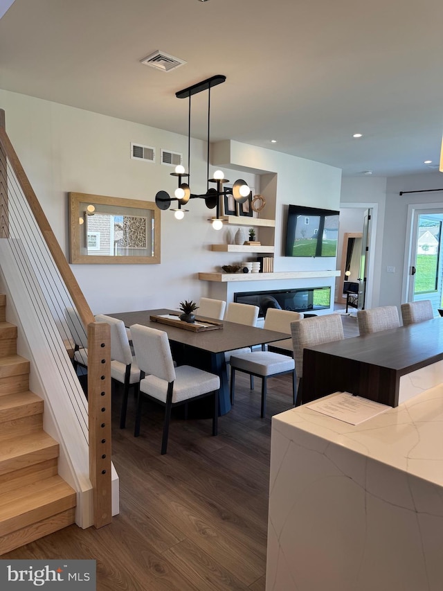 dining room with visible vents, dark wood finished floors, stairway, and an inviting chandelier