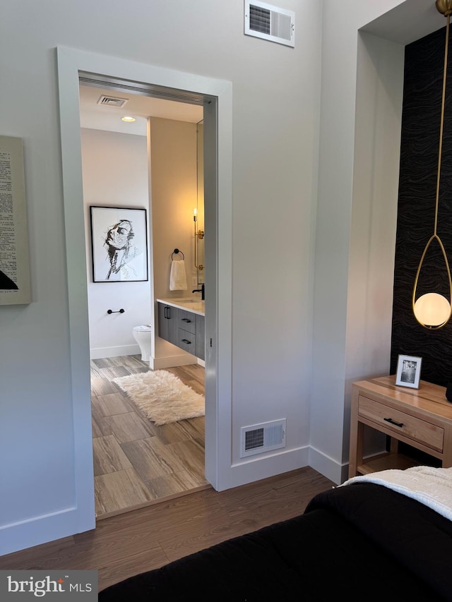 bedroom with wood finished floors, visible vents, and baseboards