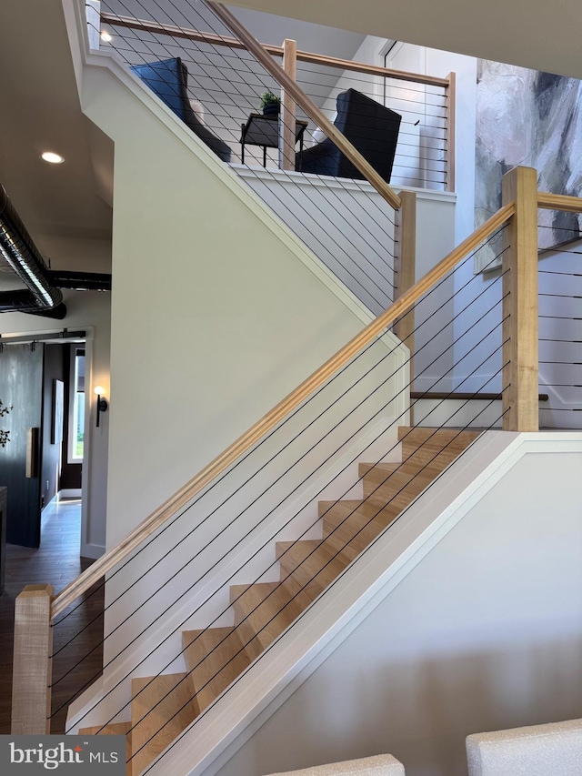 stairs with wood finished floors and recessed lighting