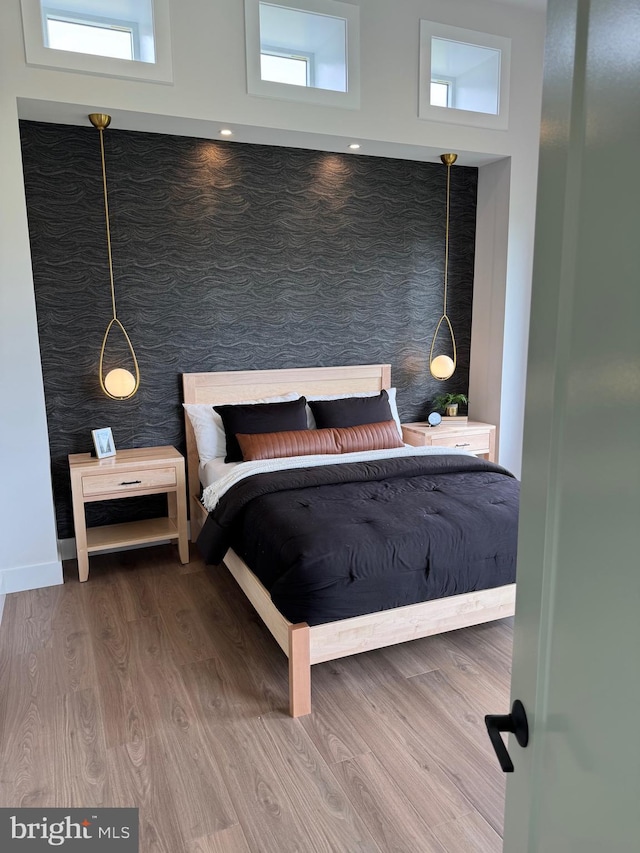 bedroom with multiple windows, baseboards, and wood finished floors