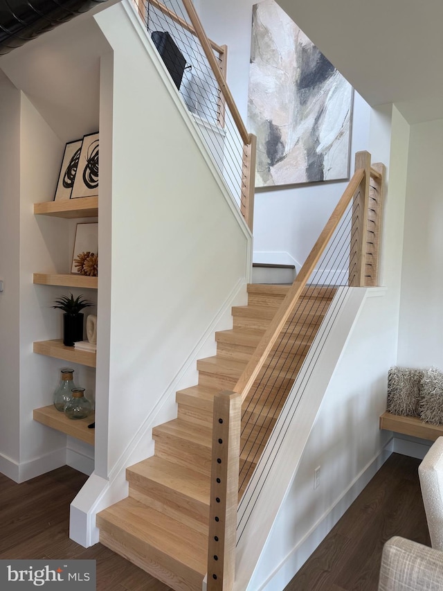 stairs featuring wood finished floors, built in features, and baseboards