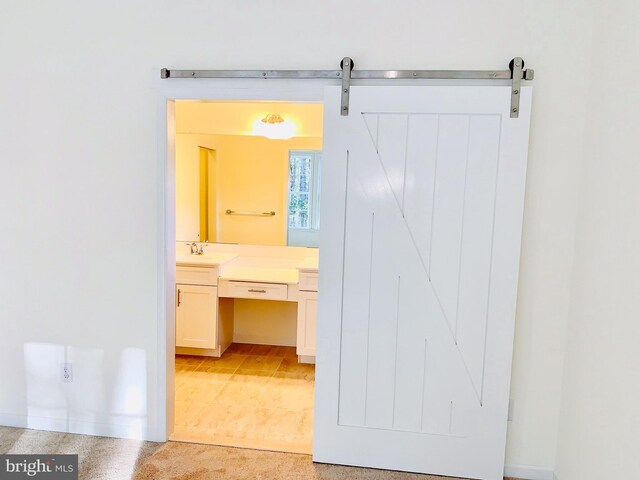 hallway with a barn door and light colored carpet