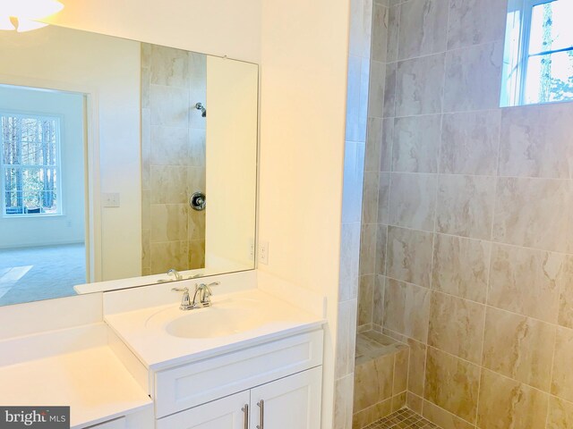 bathroom featuring a healthy amount of sunlight, a tile shower, and vanity