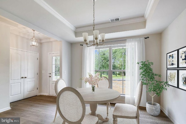 dining area with an inviting chandelier, ornamental molding, a tray ceiling, and wood-type flooring