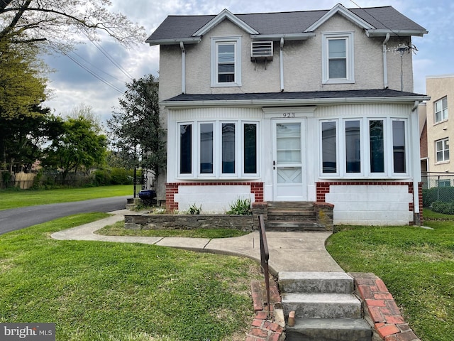 view of front of house with a front yard and a wall mounted air conditioner