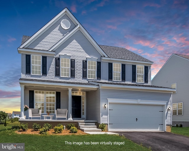 front facade featuring a lawn, a porch, and a garage