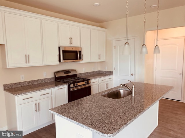 kitchen with dark hardwood / wood-style floors, a center island with sink, appliances with stainless steel finishes, and sink