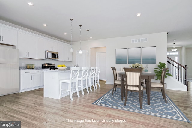 interior space featuring a center island with sink, light wood-type flooring, and white refrigerator