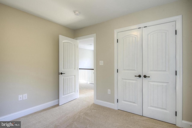 unfurnished bedroom featuring light carpet and a closet