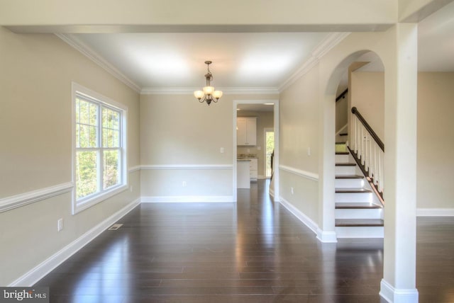 empty room featuring dark hardwood / wood-style flooring, crown molding, and a notable chandelier