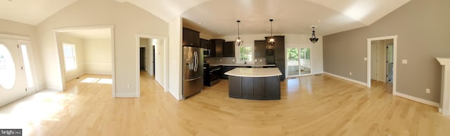 kitchen featuring decorative light fixtures, light hardwood / wood-style floors, stainless steel refrigerator with ice dispenser, a kitchen island, and dark brown cabinetry