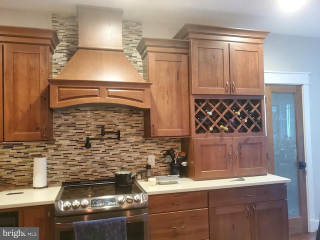 kitchen with backsplash, premium range hood, and electric range oven