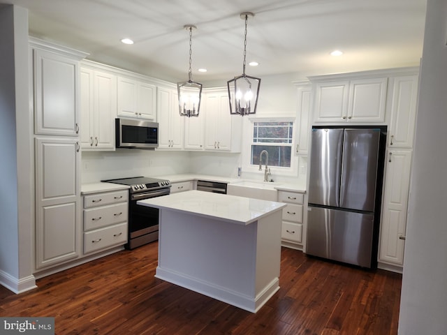 kitchen featuring dark hardwood / wood-style floors, appliances with stainless steel finishes, sink, white cabinets, and a center island