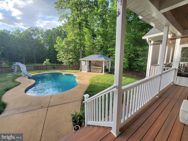 view of swimming pool featuring a patio, an outdoor structure, a yard, and a water slide