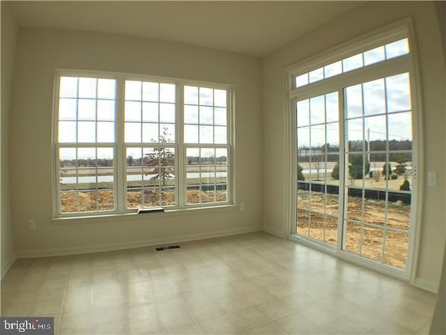 spare room featuring light tile flooring and a wealth of natural light