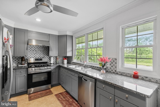 kitchen with ceiling fan, sink, light tile floors, dark stone counters, and appliances with stainless steel finishes