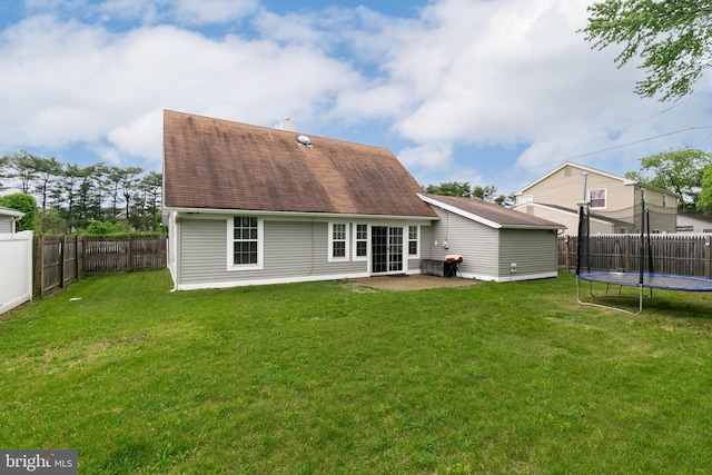 back of house with a lawn, a patio, and a trampoline