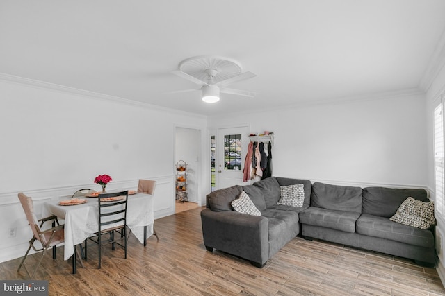 living room with ornamental molding, ceiling fan, light wood-type flooring, and a wealth of natural light