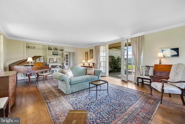 living room with built in shelves, ornamental molding, and dark hardwood / wood-style floors