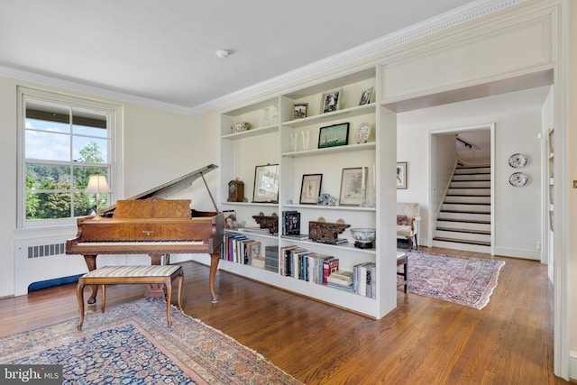 living area featuring hardwood / wood-style floors, built in shelves, radiator, and ornamental molding